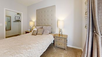 A bedroom with a bed and a nightstand with two lamps